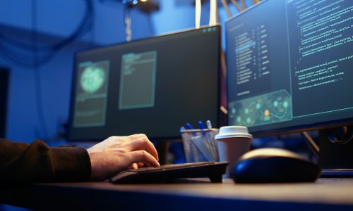Hackers typing fast on keyboard in graffiti painted hideout, rushing to finish developing spyware software, using it to gather data from users computers without their knowledge, camera A close up